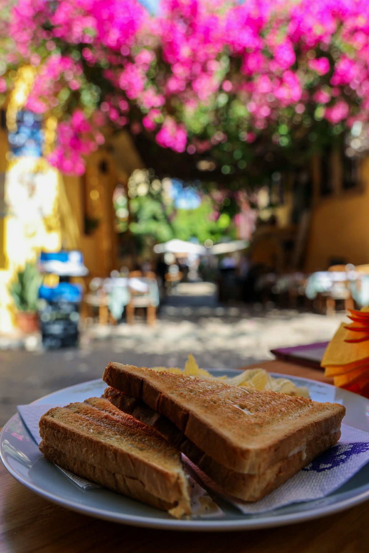Toasted sandwich on a plate at a sunlit outdoor cafe in Chania Old Town, Crete, Greece