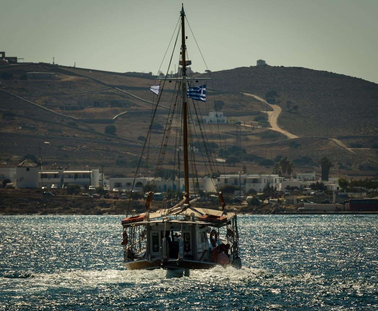 Traditional wooden sailing boat flying the Greek flag crossing the Aegean Sea