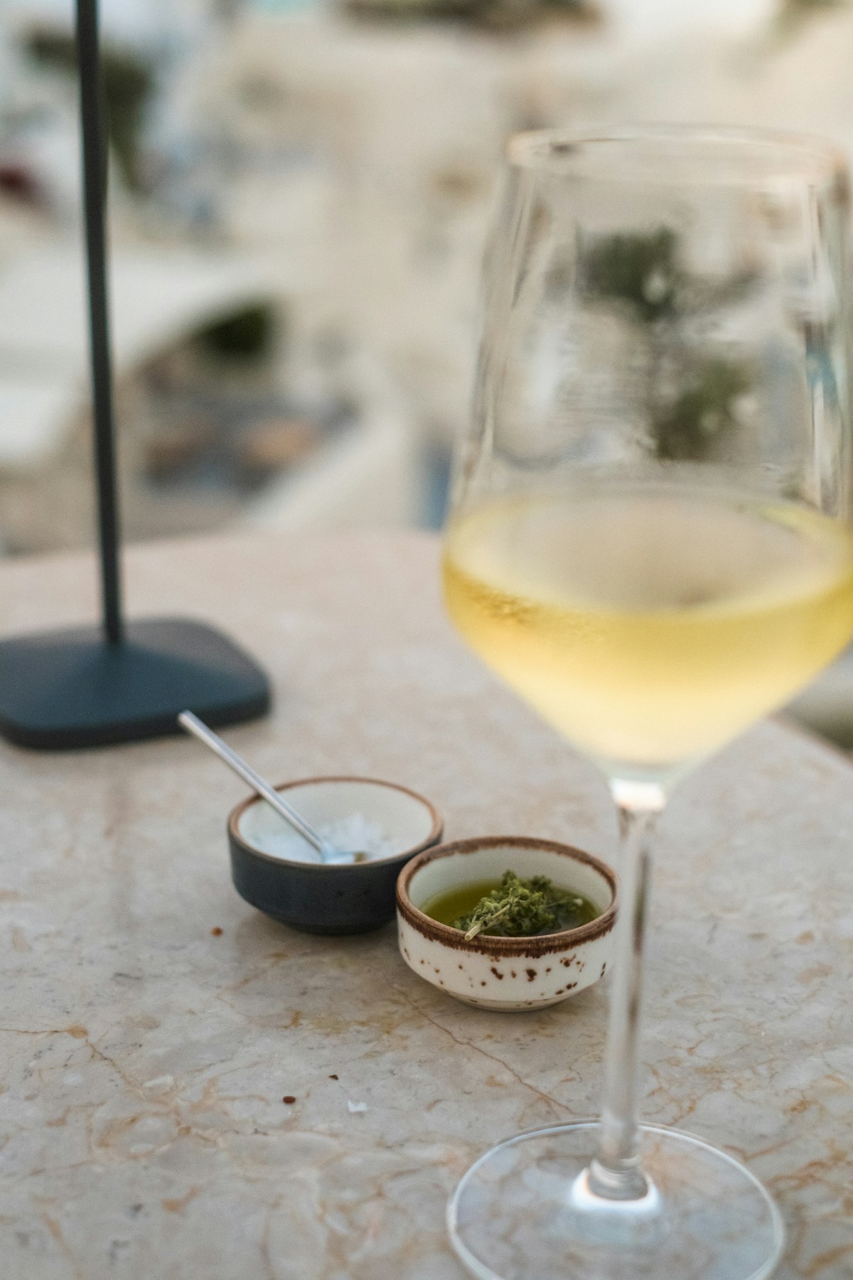 Glass of white wine with small condiment dishes on a marble table, Santorini, Greece