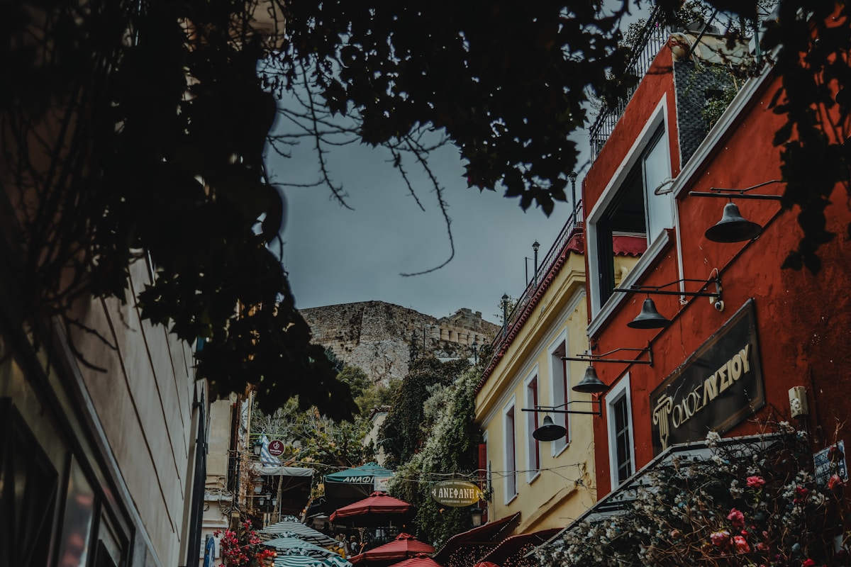 Colourful buildings on a narrow street in Plaka, Athens, with the Acropolis hill rising behind