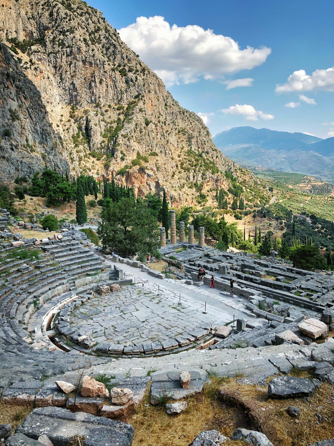 The ancient theatre and columns of the Temple of Apollo at Delphi, Greece, looking south over the deep olive-filled valley of Phocis to the Gulf of Corinth
