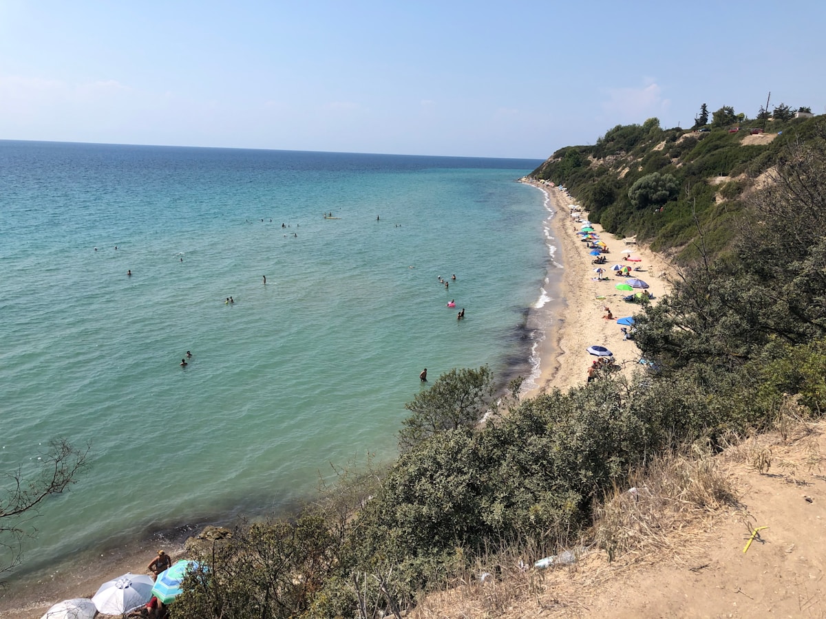 Beach with colourful sun umbrellas and clear turquoise water viewed from the hillside, Halkidiki, Greece