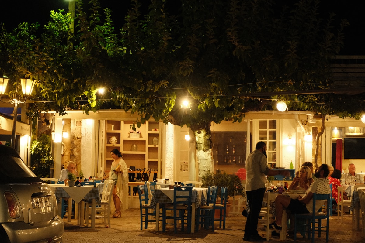 Outdoor taverna at night with blue and white chairs under a large tree, Hersonissos, Crete, Greece