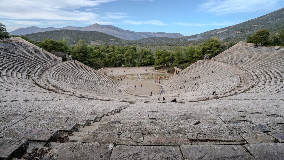 The ancient theatre of Epidaurus in the Argolid, Greece, its stone seats rising in a perfect semicircle against a backdrop of forested hills