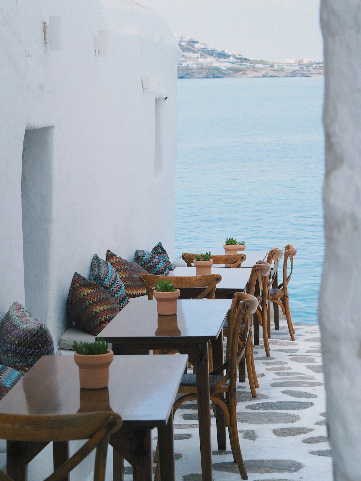 Outdoor dining terrace overlooking the sea, whitewashed walls and wooden furniture, Greece