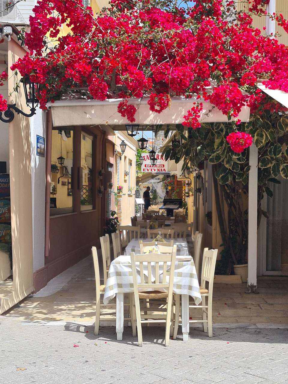 Outdoor taverna tables along the Patras waterfront with the Gulf of Corinth in the background