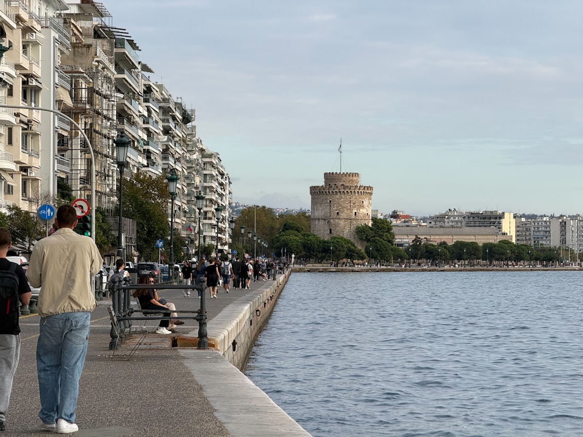 People walking along the Thessaloniki waterfront promenade with the White Tower visible