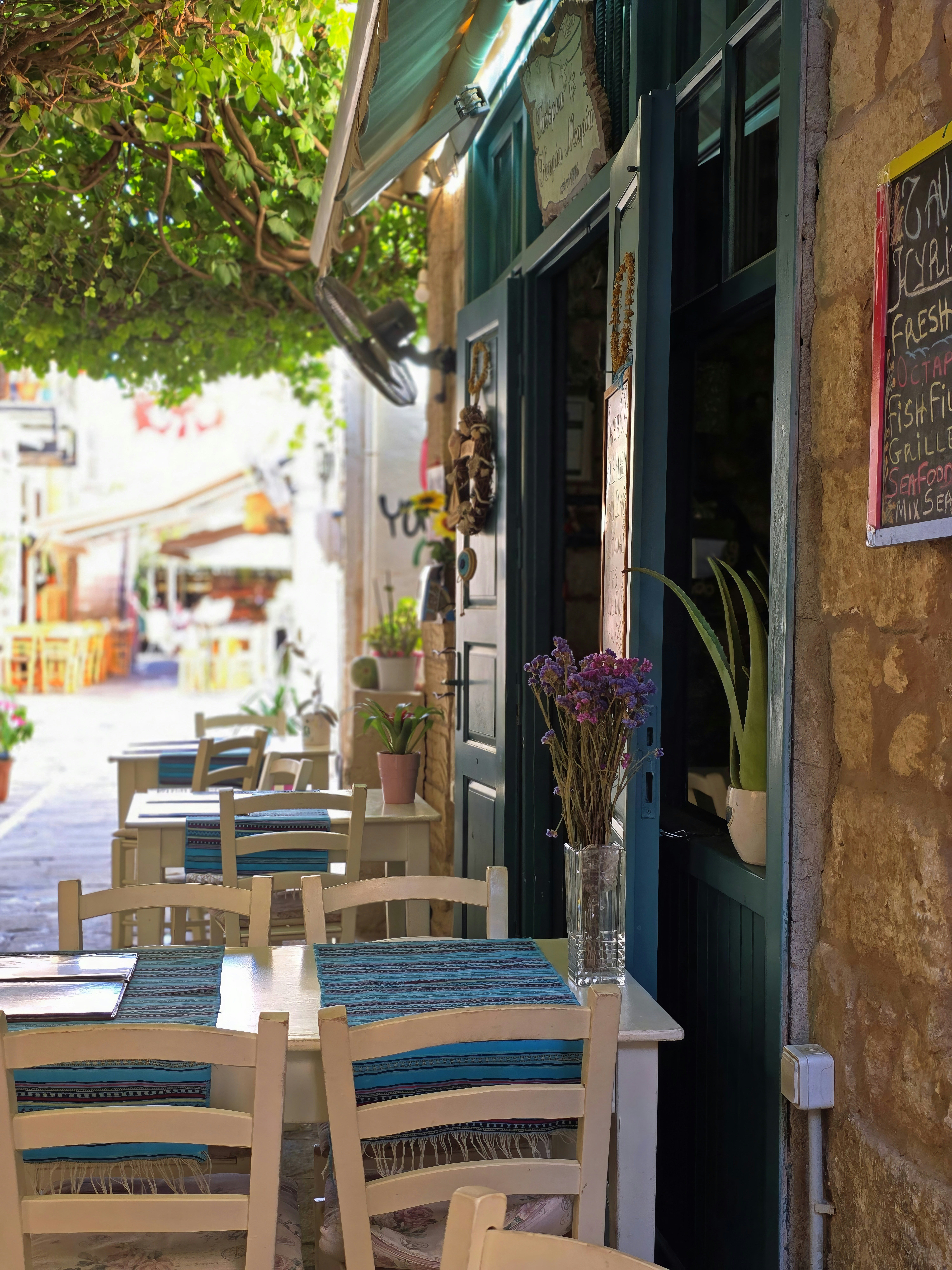 Outdoor cafe tables and chairs on a narrow stone alleyway in Rethymno, Crete, Greece