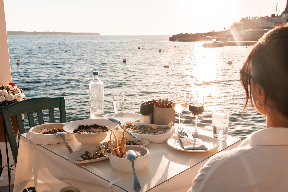 Sunset dinner table with plates of food and wine glasses overlooking the Santorini caldera
