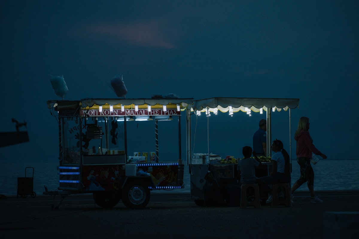 Street food cart with Greek text signs at the Thessaloniki waterfront at dusk
