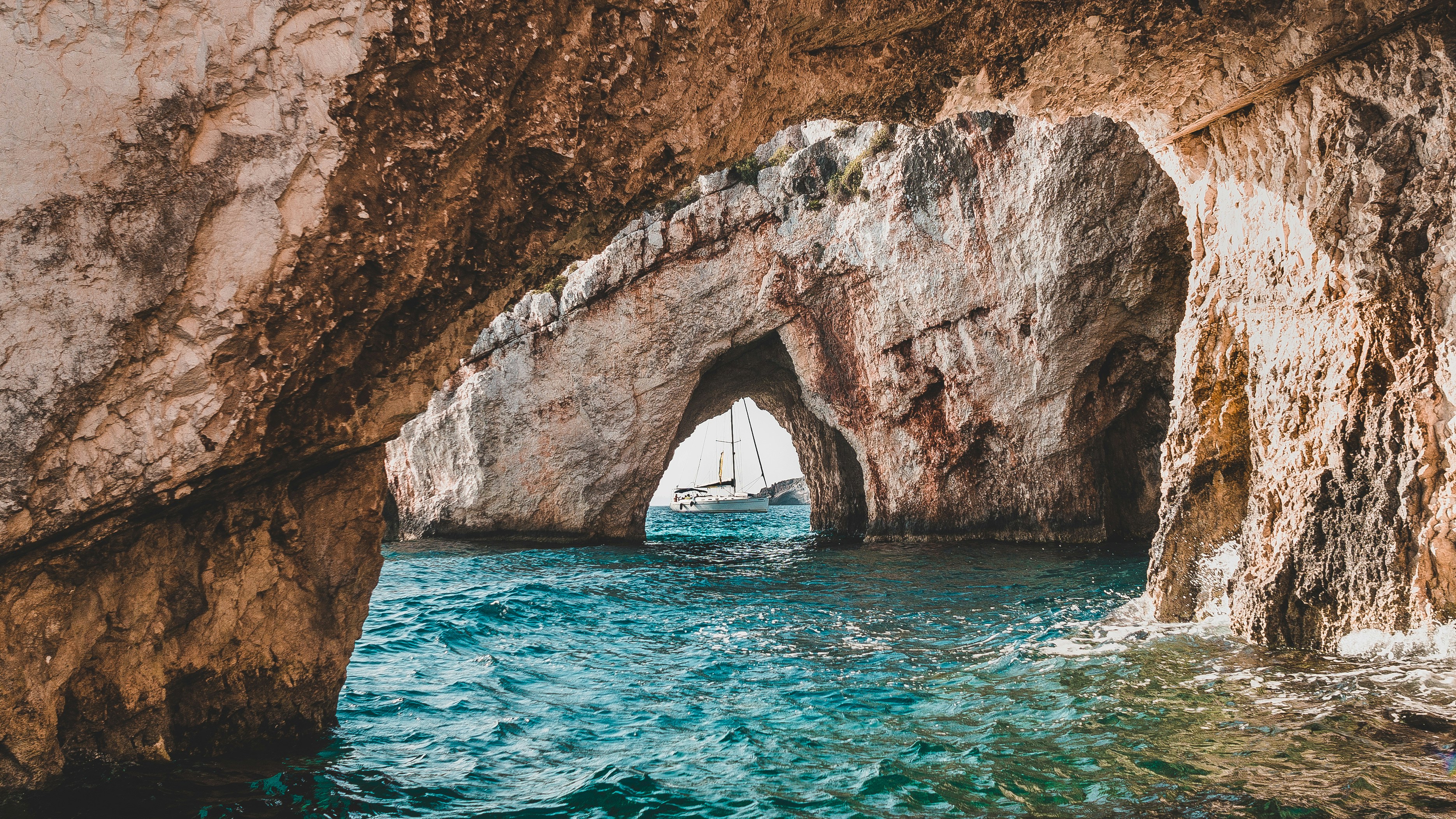 Sailboat visible through the natural stone archway of the Blue Caves, Zakynthos, Greece