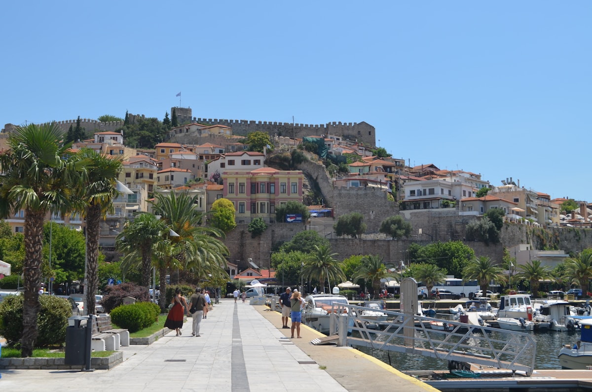 Promenade along a harbour with a historic castle on the hill, Kavala, Greece