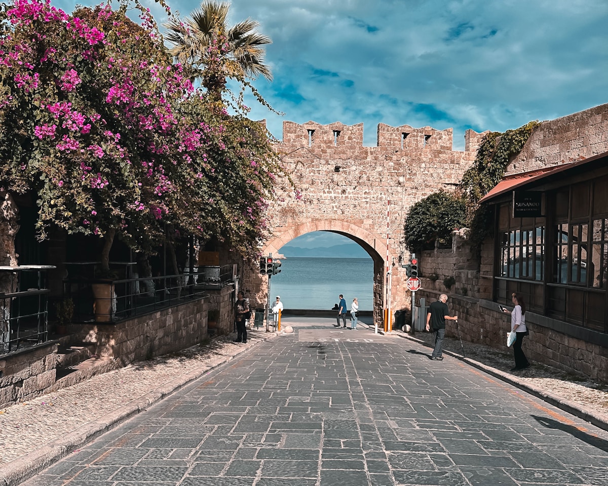 Cobblestone street with a stone arch framing a view to the sea, Rhodes Old Town, Greece