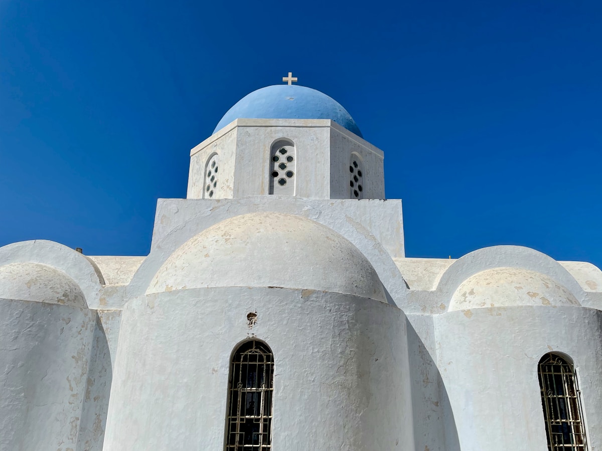 White building with a blue dome against a clear blue sky, Pyrgos, Santorini, Greece