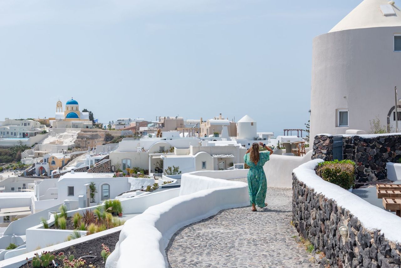Visitor walking a whitewashed path in Oia, Santorini