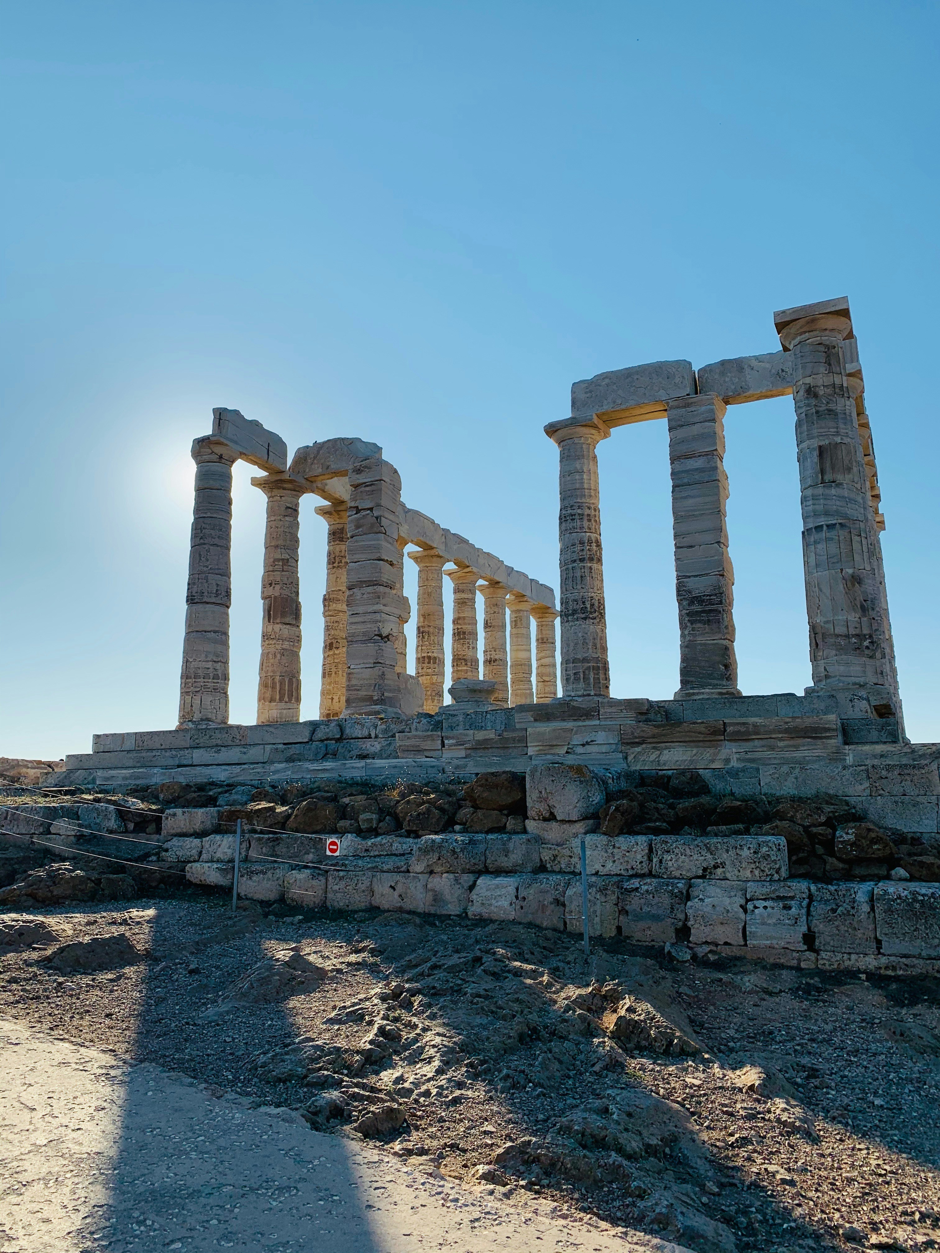 White marble columns of the Temple of Poseidon at sunset on the cliff edge at Cape Sounion