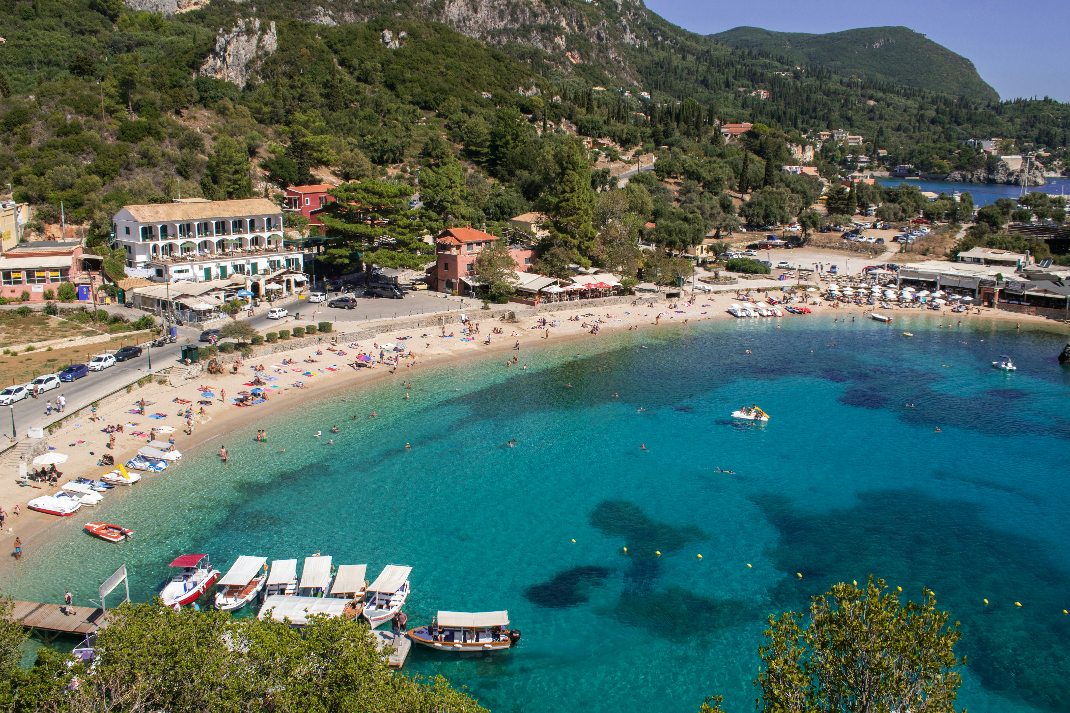 Aerial view of boats on turquoise sea near green mountains, Paleokastritsa, Corfu, Greece