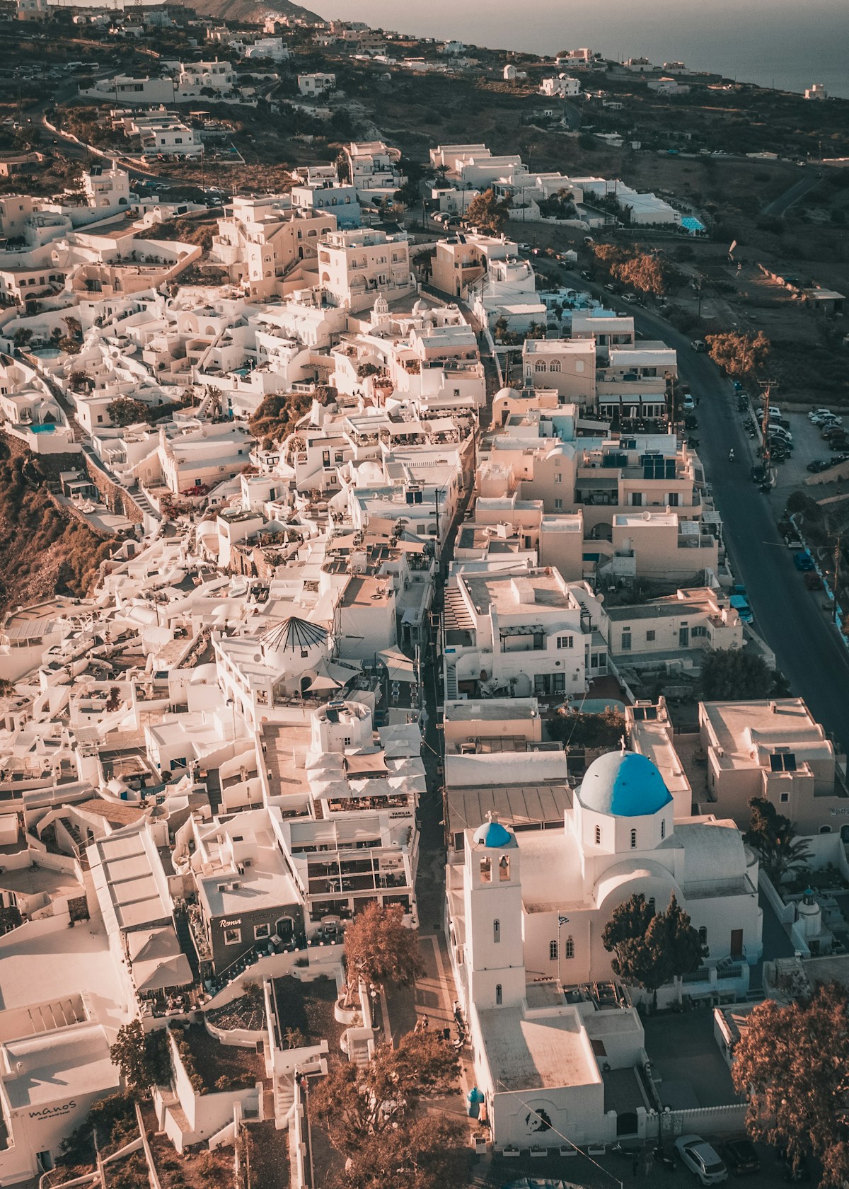 Aerial view of white Cycladic village on a rocky hilltop above the deep blue Aegean Sea