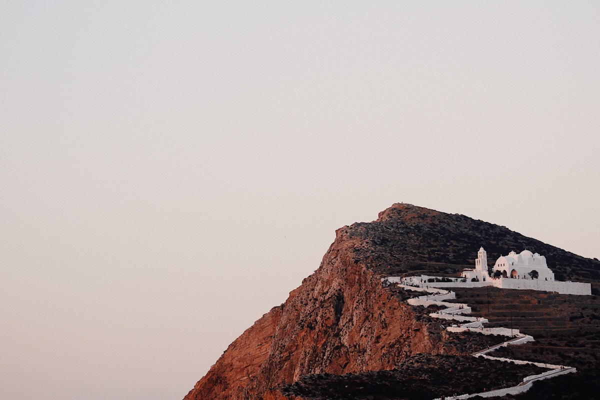The whitewashed Panagia church perched on a dramatic cliff at dusk, Folegandros, Greece