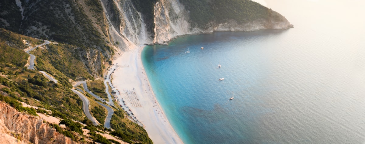 Aerial view of Myrtos Beach in Kefalonia, showing white pebbles and turquoise water against dramatic cliffs