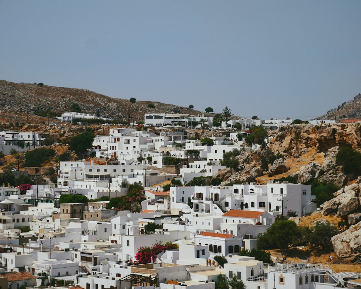 White buildings with pink bougainvillea nestled on a rocky hillside in the Dodecanese, Greece