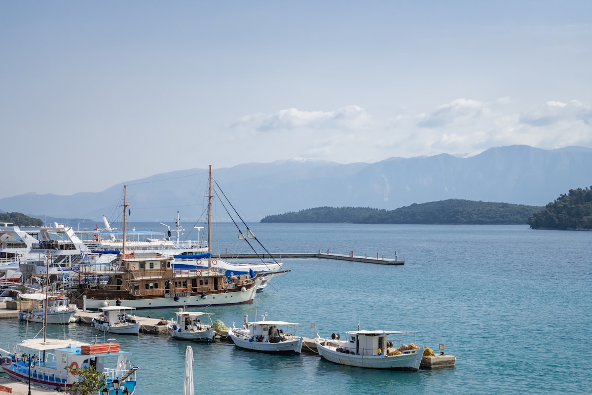 Boats docked in the calm harbour of Nidri, Lefkada, with forested mountains visible across the bay
