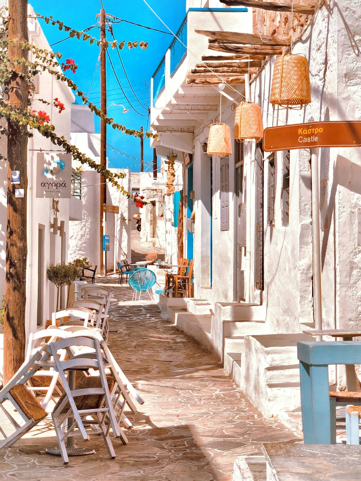 White and blue outdoor cafe chairs on a cobblestone street in the Cyclades, Greece