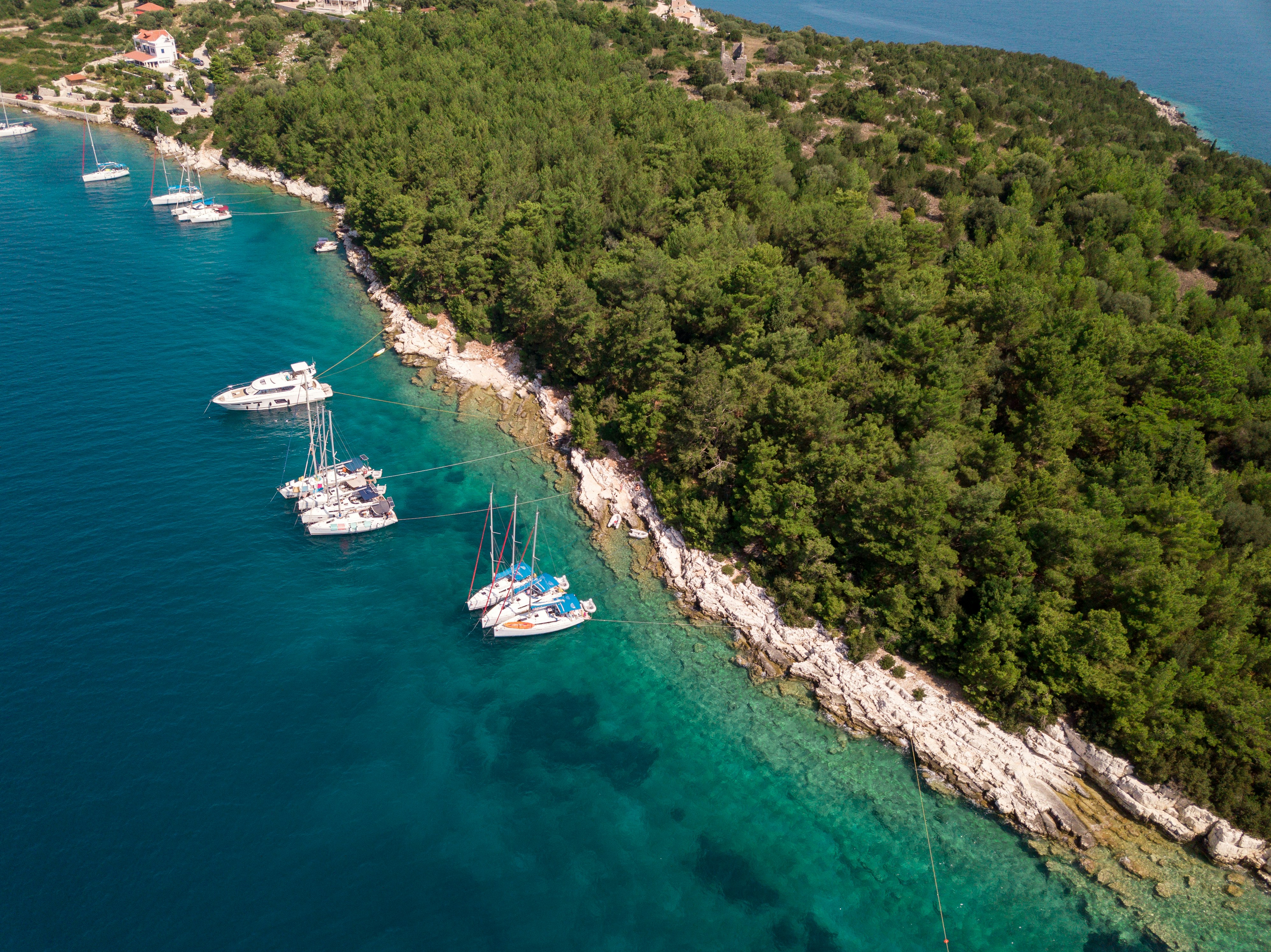 Aerial view of turquoise water and sailing boats anchored along the rocky Naxos coastline