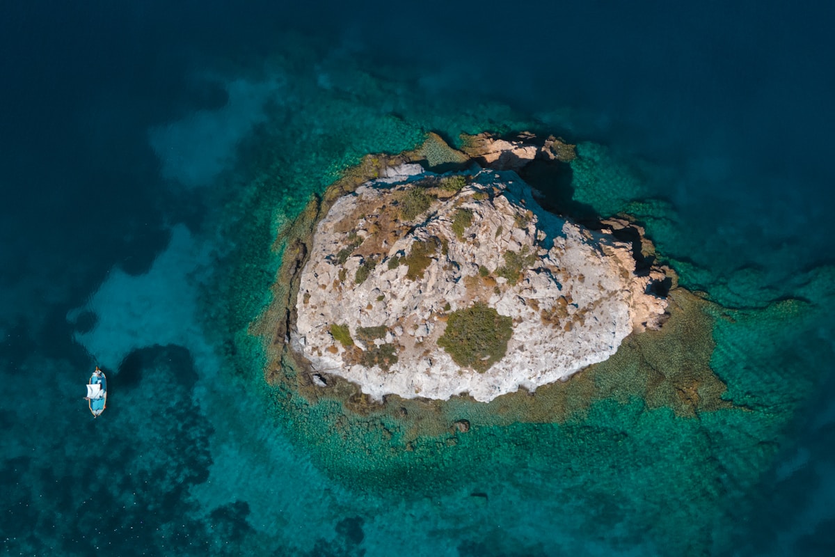 Aerial view of a small rocky islet in crystal turquoise water, Patmos, Dodecanese, Greece