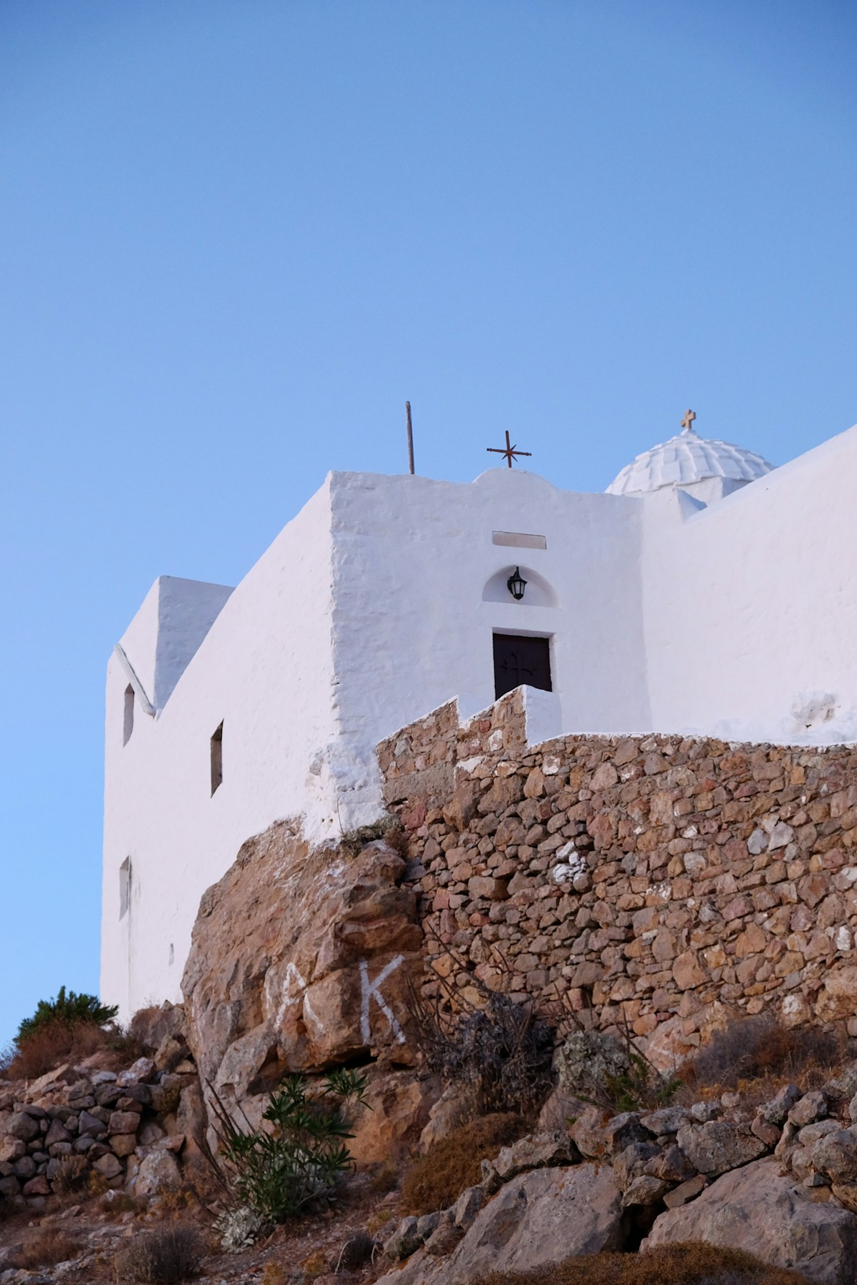 White Byzantine chapel with cross on a rocky hillside on Patmos, Dodecanese, Greece