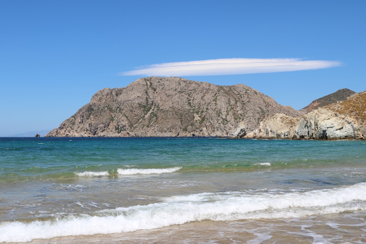 Turquoise beach with clear water and dramatic mountain backdrop, Patmos, Dodecanese, Greece