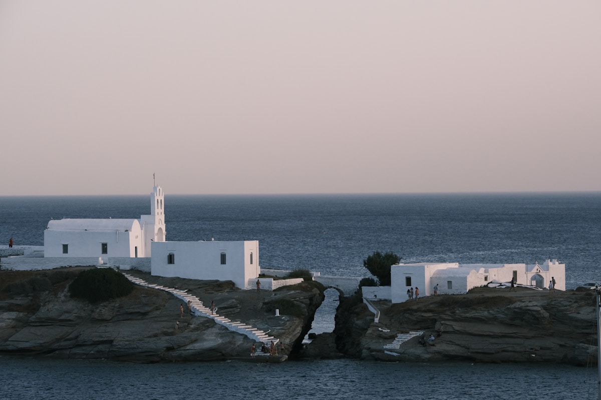 Chrissopigi monastery on rocky headland with white chapel and stone steps above the sea, Sifnos, Greece