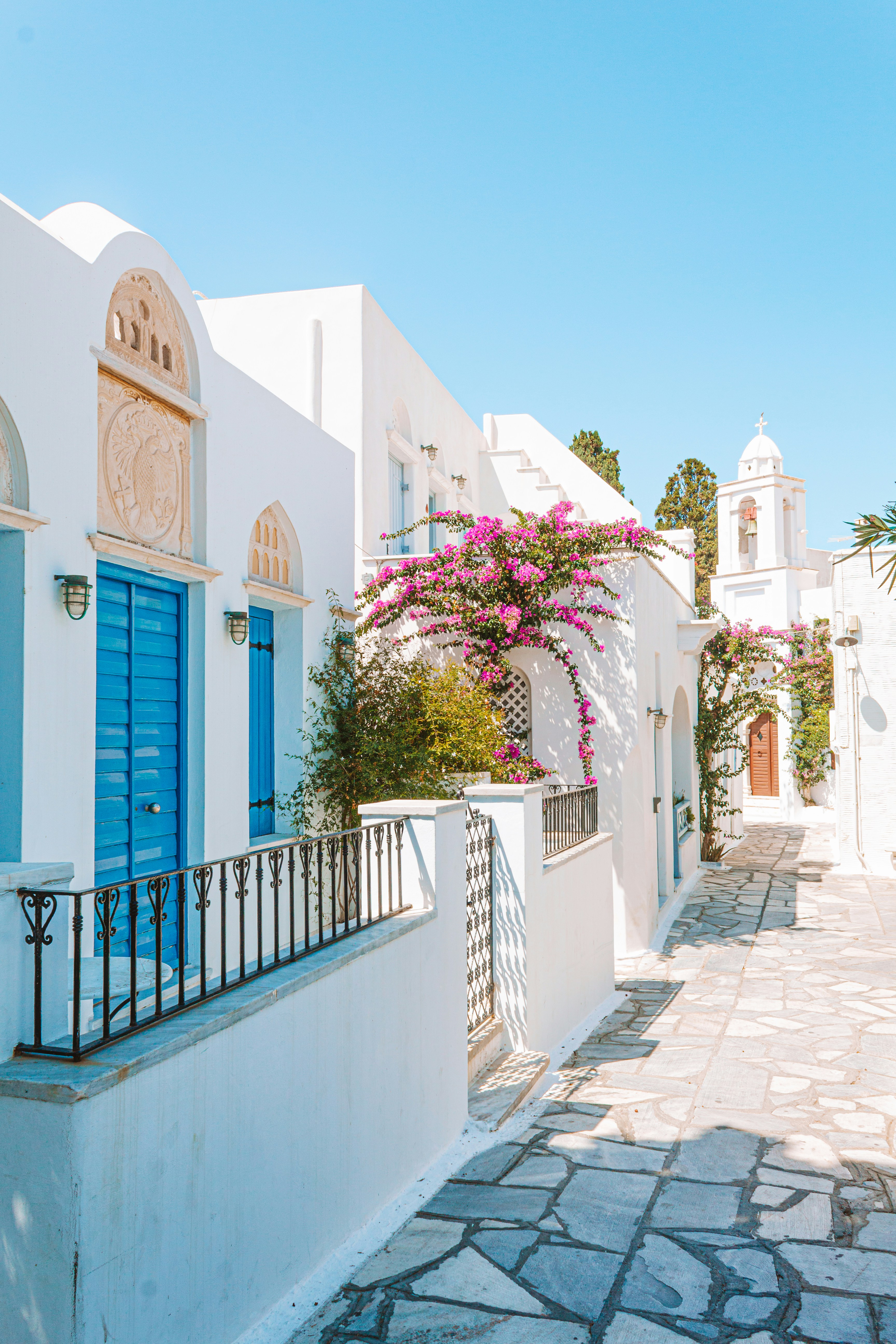Whitewashed alleyway with blue doors and bougainvillea in a Cycladic village, Greece
