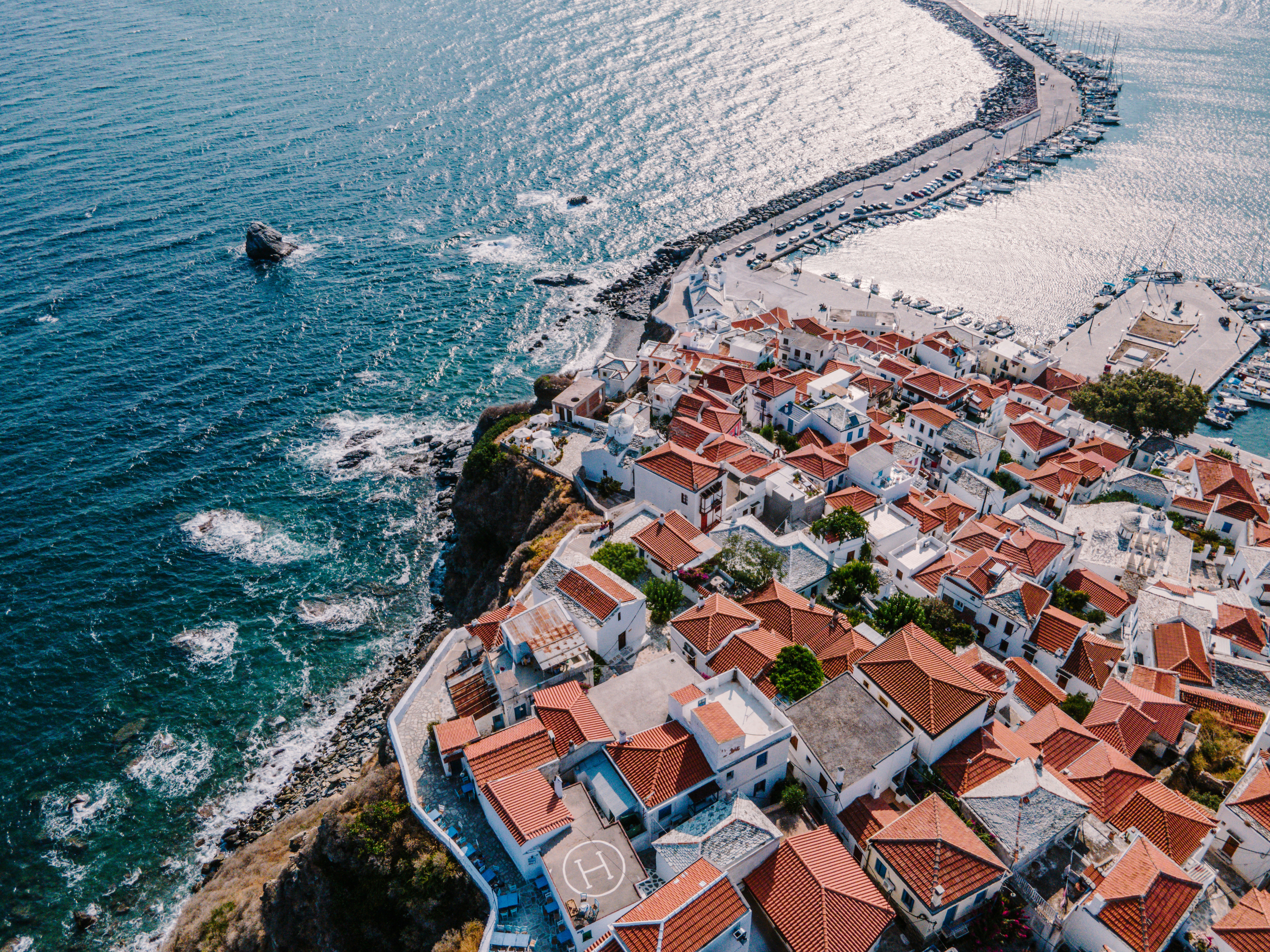 Aerial view of Skopelos town with white buildings and red-tiled roofs along the harbour, Greece
