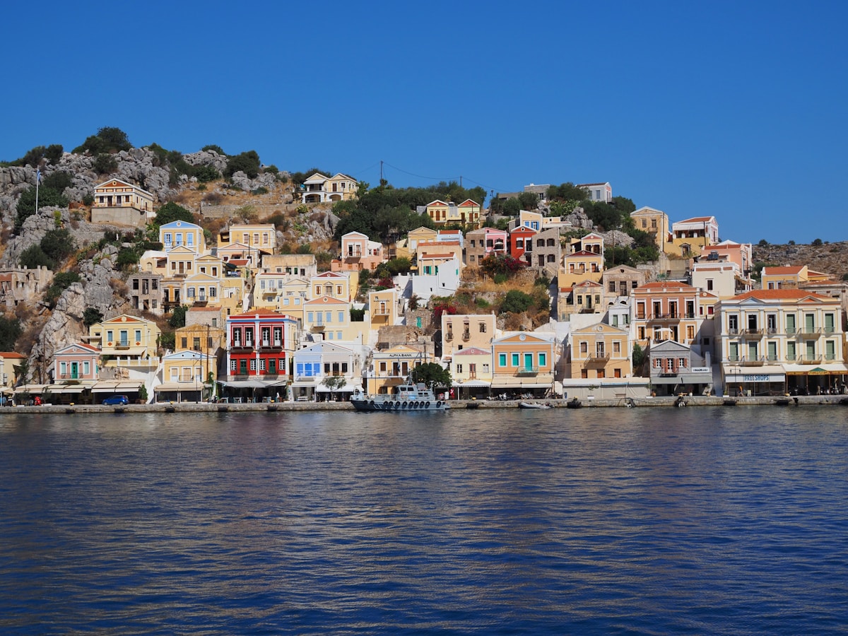 Colourful neoclassical mansions rising above the harbour waterfront, Symi island, Dodecanese, Greece