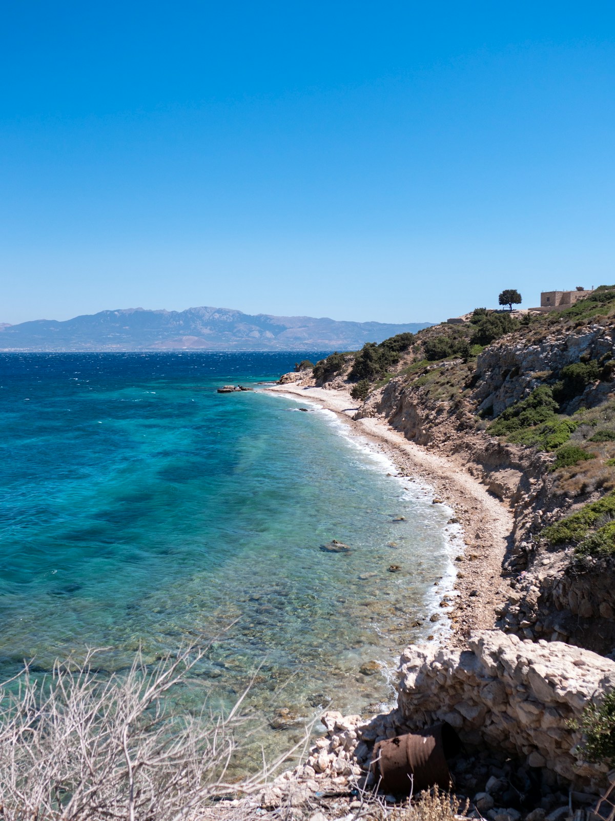 Rocky coastline with turquoise clear water and clifftop ruins, Dodecanese Islands, Greece