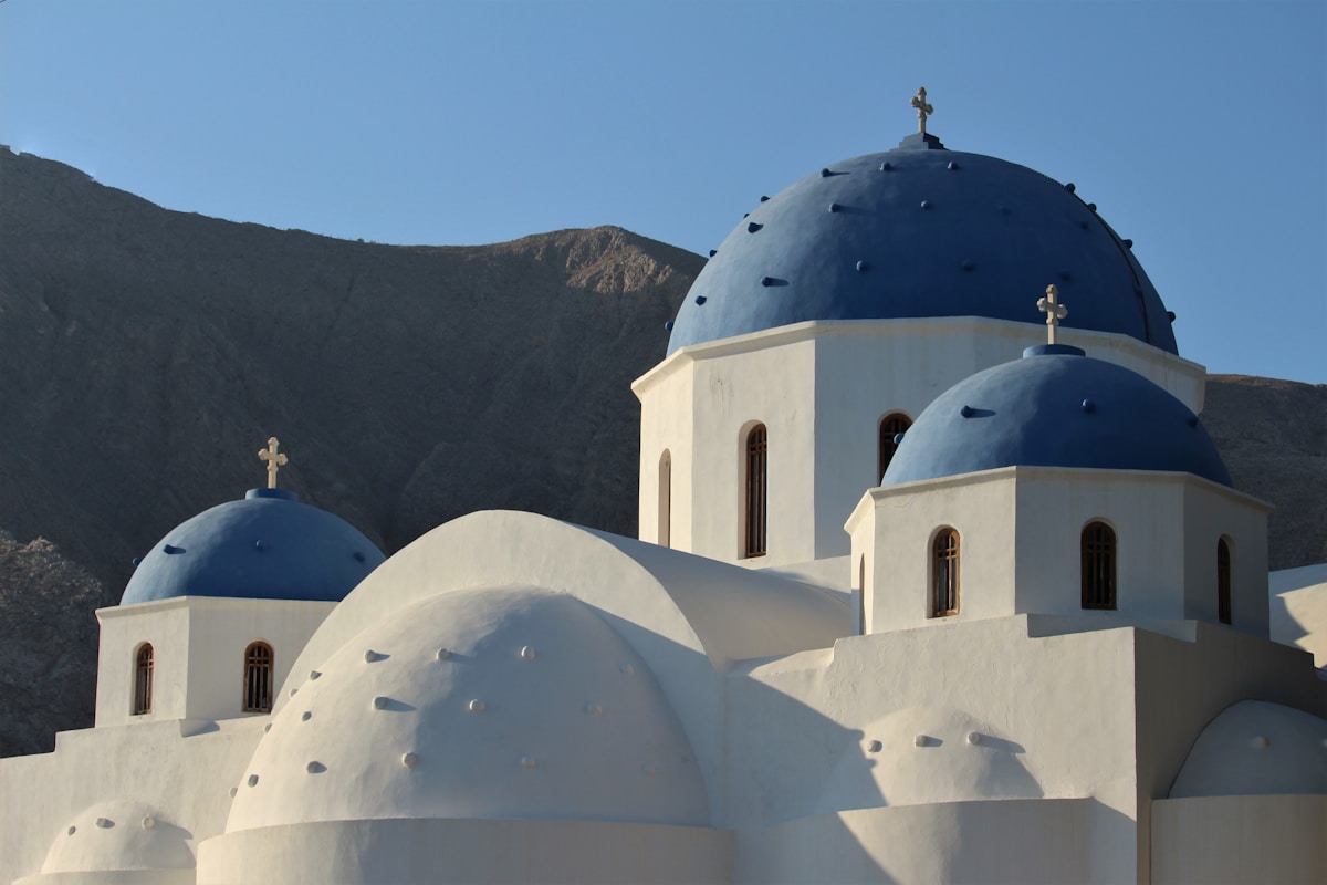 Blue-domed church against volcanic mountains, Santorini, Greece