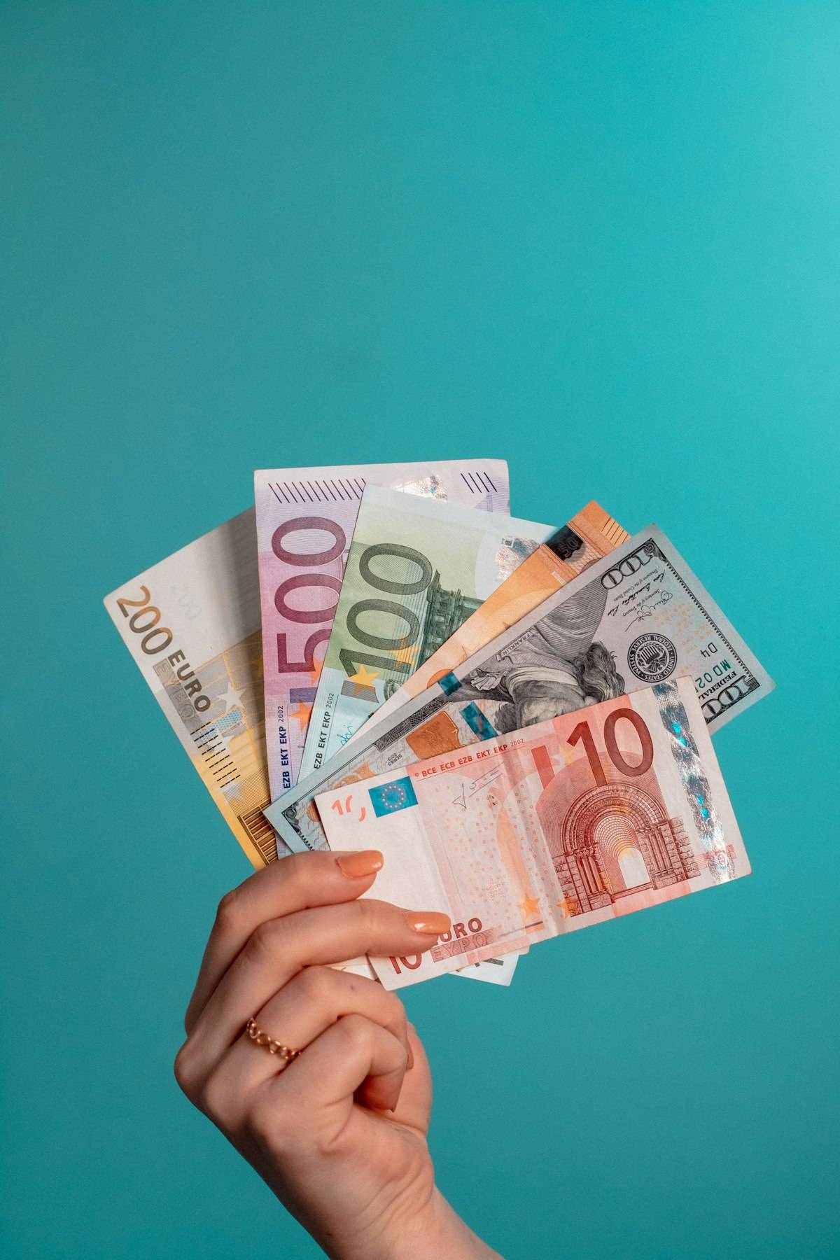 Hand holding fanned-out euro banknotes including 200, 100 and 10 denominations