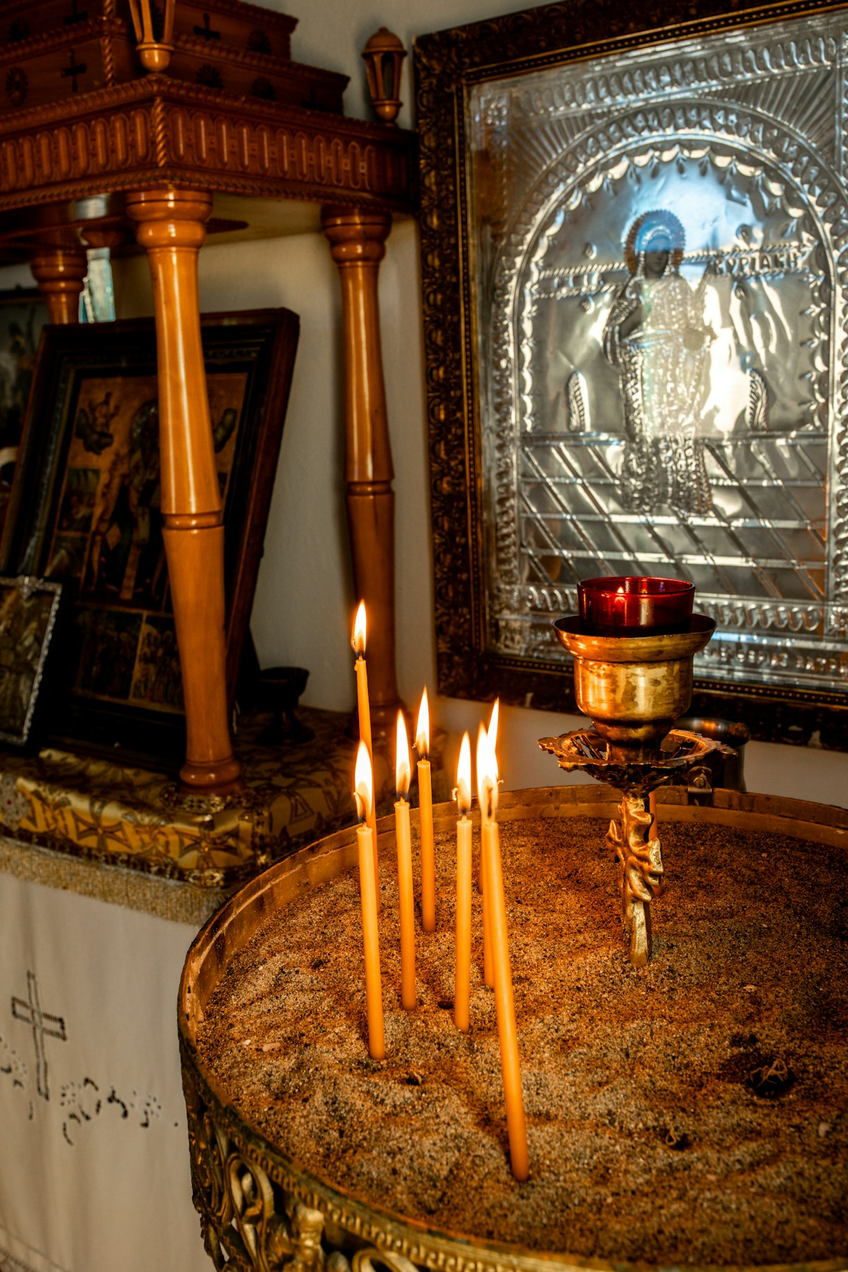 Lit candles placed before gilded religious icons inside a Greek Orthodox church in Milos, Greece