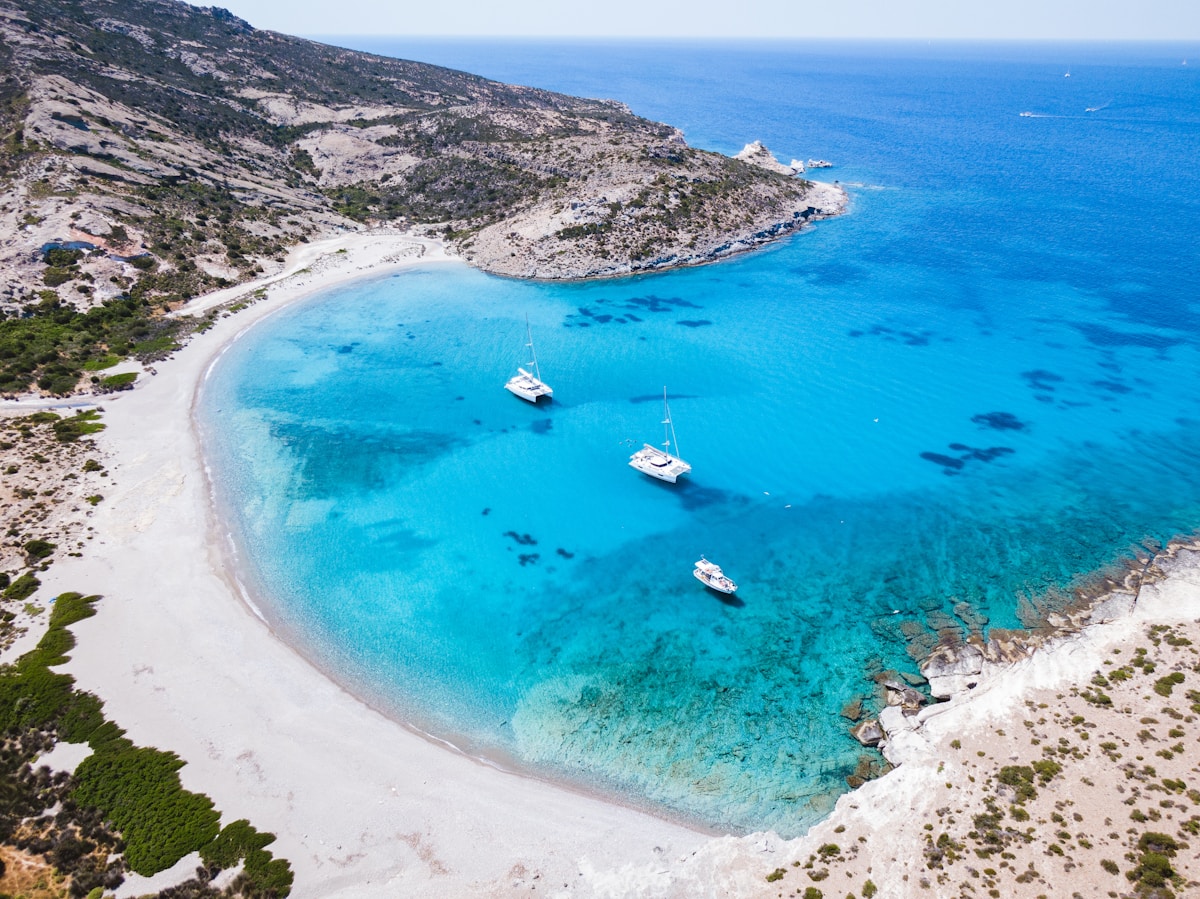 A smartphone with a Greek island map visible on screen and blue sea in the background