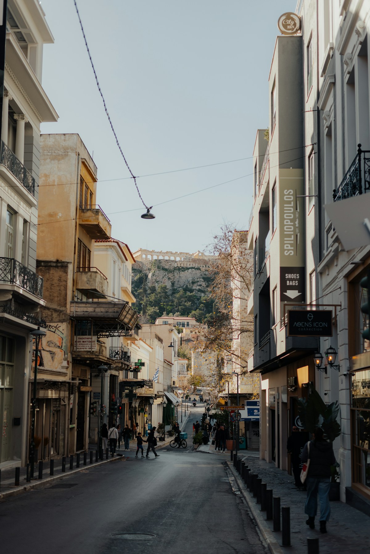 Athens street scene with the Acropolis visible in the background and Greek shop signs