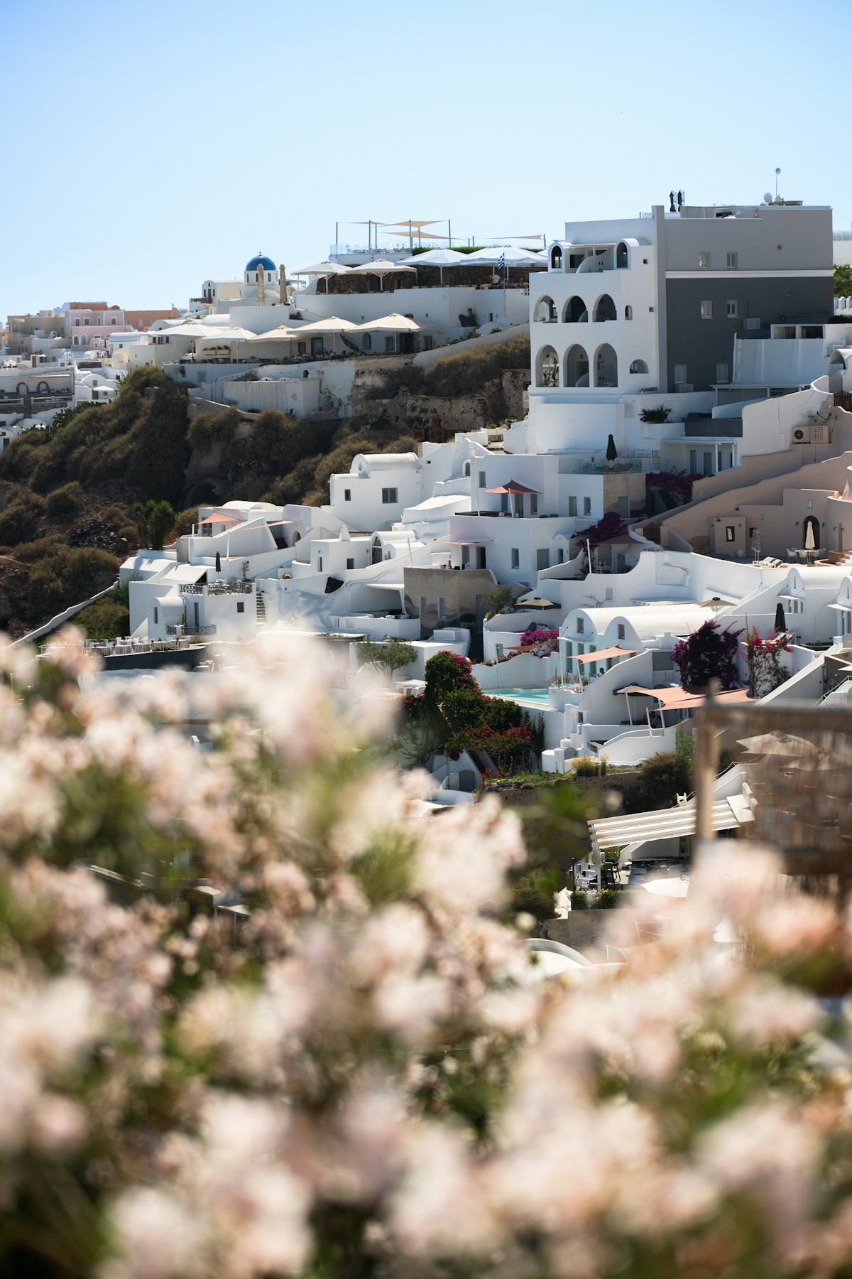 White-washed buildings and blue-domed church on a sunny hillside in Oia, Santorini, Greece