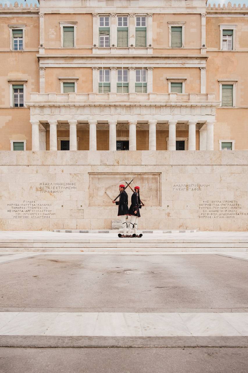 Two Evzone guards in traditional uniform in front of the Hellenic Parliament and Tomb of the Unknown Soldier, Athens