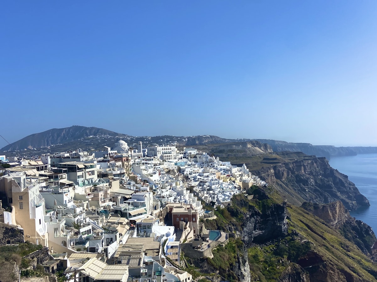 Fira village perched on the volcanic caldera cliffs of Santorini, Greece, with white buildings cascading toward the Aegean Sea