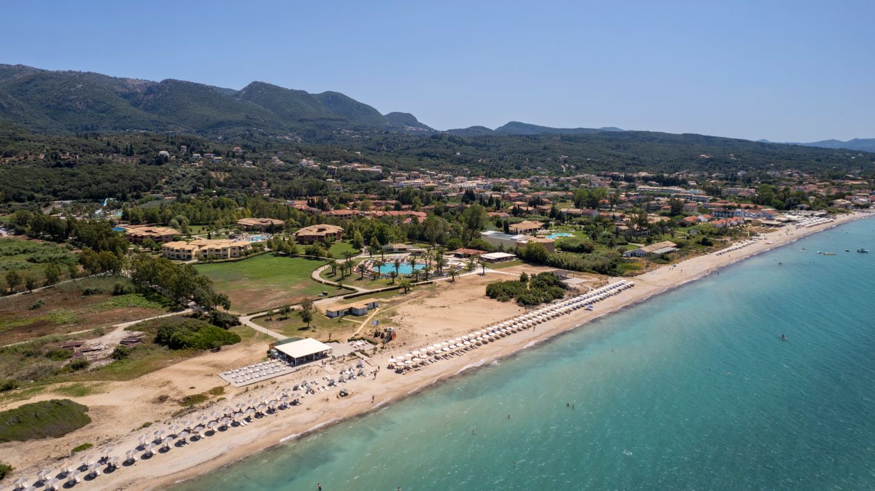 Aerial view of a beachfront resort in Corfu, Greece with turquoise sea and forested hills