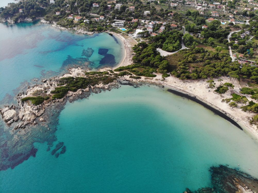 Aerial view of turquoise coves and pine-forested coastline on the Sithonia peninsula, Halkidiki, Greece