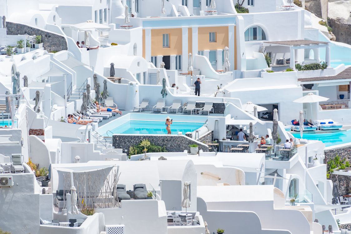 Luxury Santorini resort with whitewashed Cycladic architecture, infinity pools and sunbeds overlooking the caldera