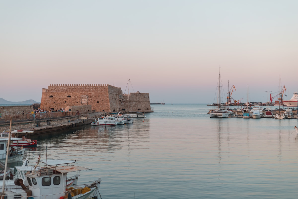 Koules Venetian fortress at Heraklion harbour glowing at sunset with boats moored in the calm water