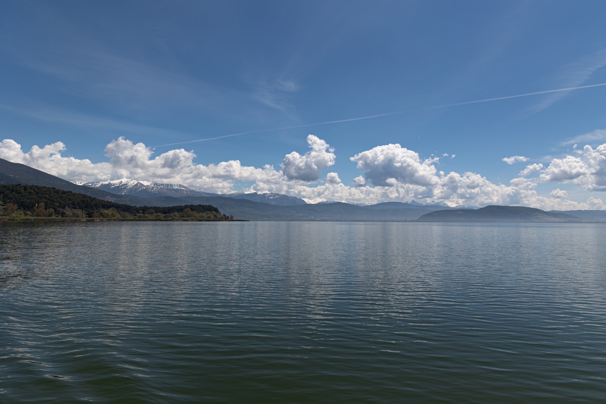 Lake Pamvotis with calm water reflecting the sky and mountains rising on the far shore near Ioannina, Greece