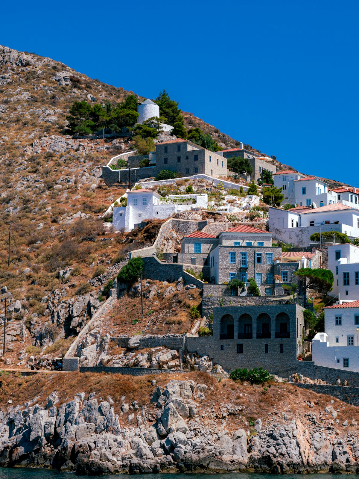 Whitewashed hillside village with windmill and stone buildings, Ios island, Cyclades, Greece